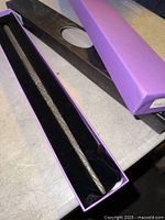Wand inside open purple box