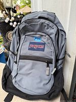 Front view of grey/black JanSport backpack showing logo and pockets