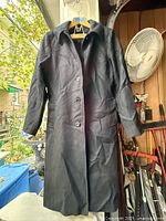 Front view of black wool coat hanging, showing buttons and collar