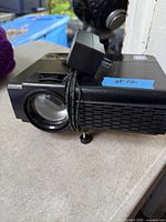 Side view of RCA projector showing lens, ventilation grille and attached power adapter