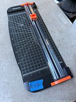 Top view of WorkLion paper cutter showing grid, ruler, clear guide rail and orange blade