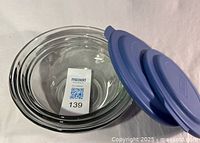 Nested clear tempered glass bowls with blue lids, size tag visible