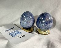 Two egg-shaped shakers standing upright beside lot tag