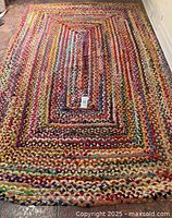 Full view of multicoloured braided cotton rag rug laid out on floor