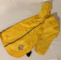Full view of yellow dog raincoat showing hood, reflective stripe, paw print, pocket