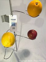 Close-up of pole, bracket, tag and three curved branches holding sample fruit