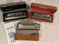 Three Hohner Special 20 Marine Band harmonicas in their cases, keys visible