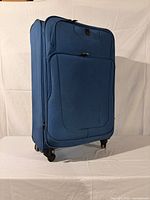 Front view of blue Travelpro suitcase showing two exterior pockets and four wheels