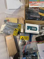 Box with assorted components, static-safe bags, blue microcontroller board