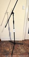 Full view of black tripod microphone stand with boom arm extended