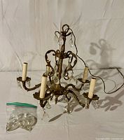 Full view of chandelier showing five arms, prisms, wiring and bag of spare crystals