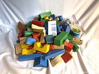 Pile of assorted coloured and natural wooden blocks with bag of construction parts visible