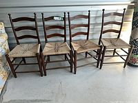 Four ladder-back chairs lined up against wall