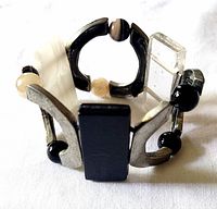 Bracelet standing upright showing mix of pewter arcs, glass panels, round beads, elastic construction