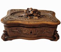 angled view of carved wooden jewelry box showing floral lid and side panels