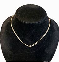 Front view of necklace on display bust showing three wires and central bead