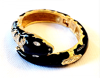 Top view of coiled black enamel serpent bangle showing crystal eyes and gold detailing