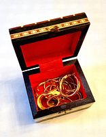 Jewelry stored in wooden inlay box with red interior