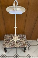 Full view of cream painted cast iron ashtray stand showing dish, handle, column, and ornate feet