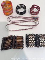 All items laid out showing three beaded cuff bracelets, two braided strands, and four slat stretch bracelets