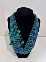 Front view of twisted multi-strand blue/green beaded necklace on display bust
