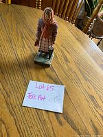 Front view of carved woman figurine on table with identification card