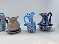 Front view of three pitchers with two basins beside a can for scale