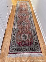 Full view of silk oriental runner on hardwood floor showing overall pattern and size