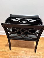 Front view of black wood magazine rack showing lattice cut-out sides and overall shape