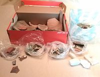 Shoebox with large quantity of ceramic shards and several plastic bags of fragments.