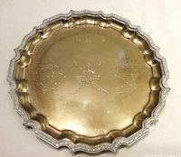 Full view of round brass tray showing scalloped rim and engravings