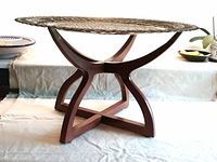 Side view of brass tray resting on folded wooden stand