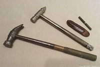 Both hammers, miniature screwdriver and leather sleeve displayed together