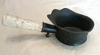 Side view of silk iron showing metal bowl and carved bone handle