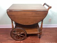 Side view leaves down showing wheels, handle, drop leaf contour, shelf