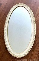 Full view of oval mirror on wood floor
