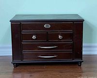 Front view of closed wooden jewellery box showing drawers and hardware