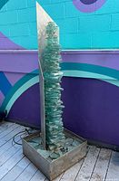 Full view of fountain showing metal base, glass tiers, and back panel