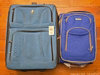 Large and small blue rolling suitcases front view