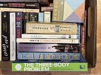 Close-up of top stack highlighting key titles including Passage, Tinkers, Islanders, Three-Body Problem