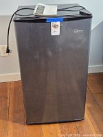 Front view of Midea compact refrigerator with manual on top