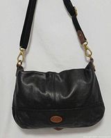 Front view of black leather Fossil tote with brown handles and detachable strap