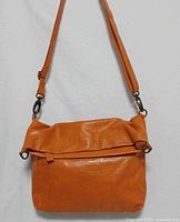 Front view showing fold-over design, zip closure, strap and hardware