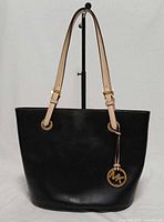 Front view of black Michael Kors Jet Set tote showing shape and MK charm