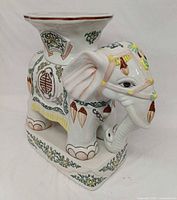 Front/side view of porcelain elephant stool showing painted details and square seat