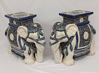 Front angled view of both ceramic elephant stools showing decorative details