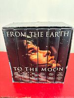 Front view of boxed six-cassette set showing spines forming astronaut face image and title