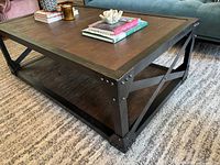 Angled view showing wood top, metal frame, rivets, and lower shelf