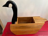 Side view of wooden planter showing black swan head and slatted body