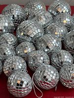 group of silver mirrored disco ball ornaments on red surface